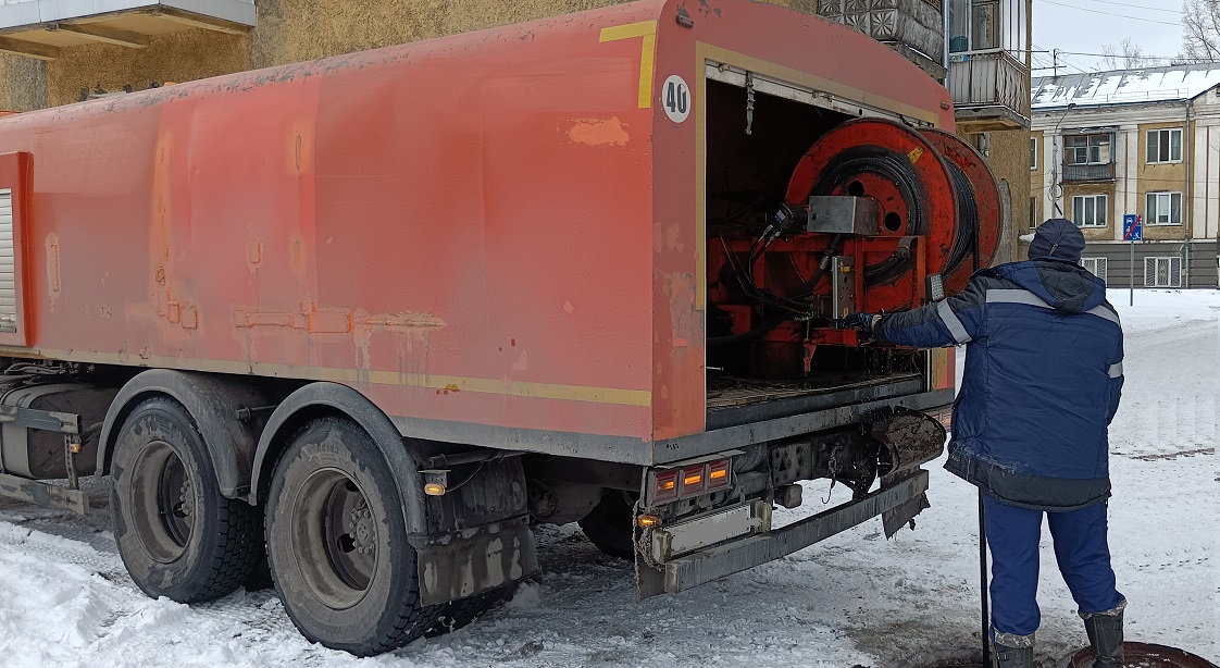 Каналопромывочная машина и работник прочищают засор в канализационной системе в Трехгорном